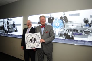 President of Illinois College of Optometry (ICO) Arol Augsburger (in bow tie) stands with his ICO President predecessor Dr. Charles Mullen in front of a mural depicting key events in the 144 year history of ICO.